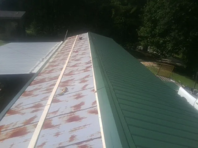 Old rusted panels beside newly installed green metal roofing — Wind Damage Roof Repair by Roofing Brothers in Nokomis
