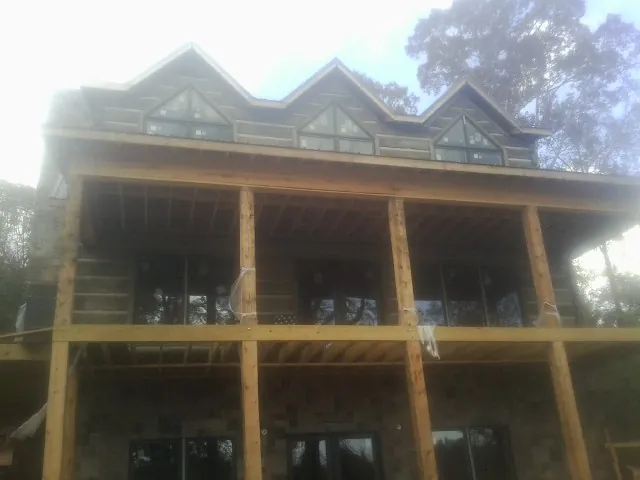 Dormers and porch framing on a large log home under construction — Roof Coating work by our crew in Nokomis