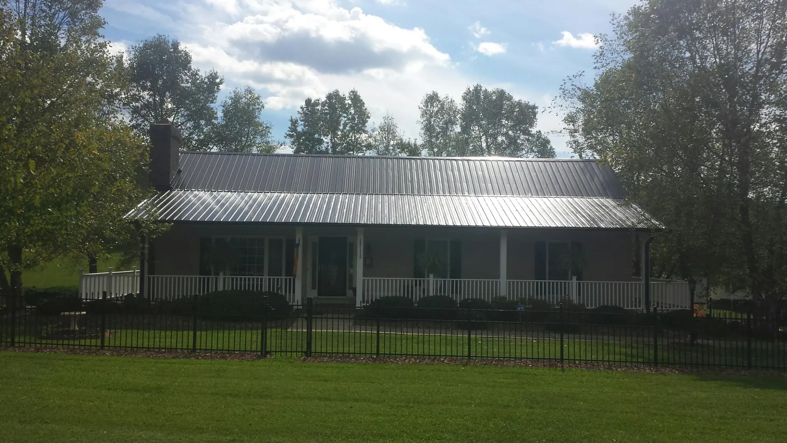 Gray metal roof on a brick ranch with a full width front porch — Gutter Guard Installation work by our crew in Nokomis