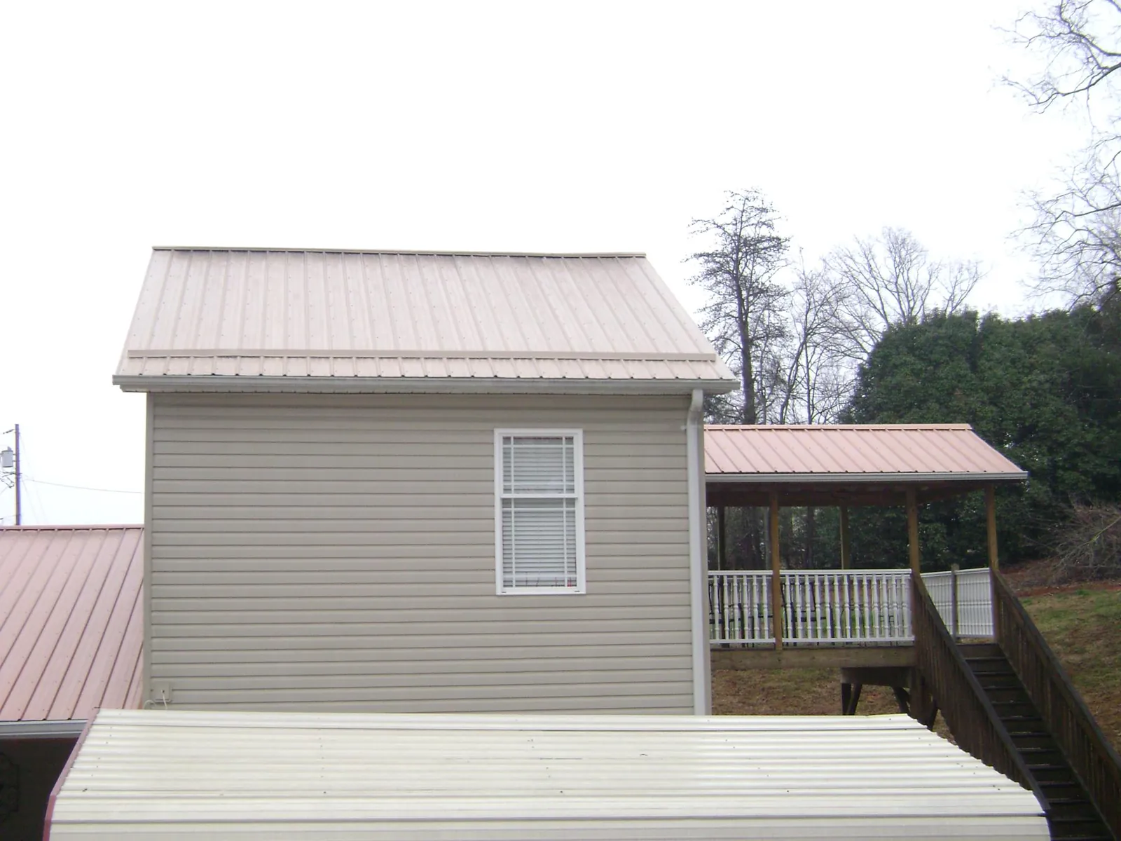 Tan metal roofs on a two story addition and attached porch, from a Roof Replacement job in Nokomis