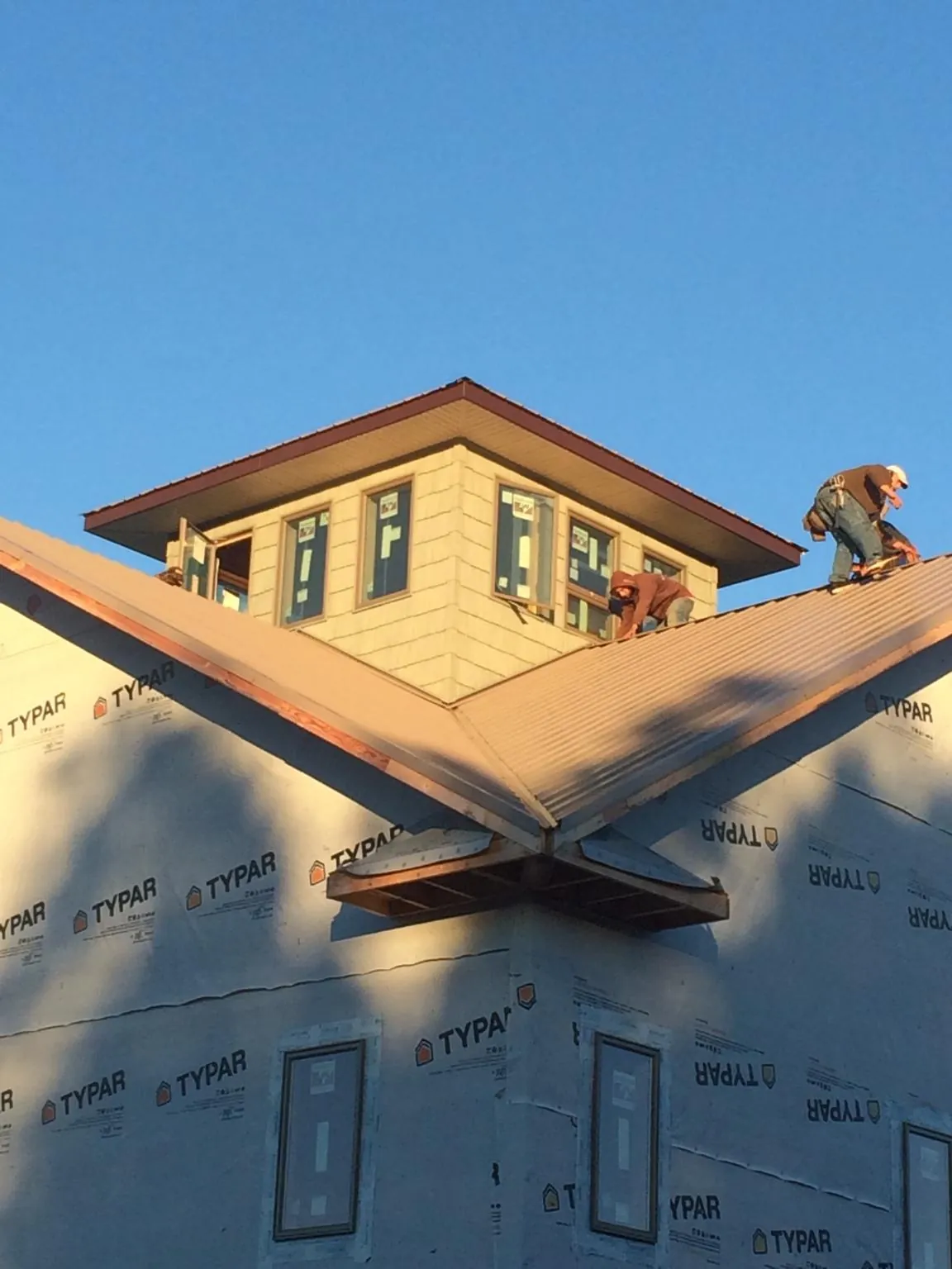 Roofers working around a rooftop cupola on a new metal roof at sunset — Roof Waterproofing in Nokomis by Roofing Brothers